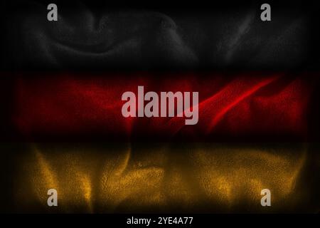 German flag illustration representing the colors of the Germany nation (black red yellow gold) with dark textured fabric background Stock Photo