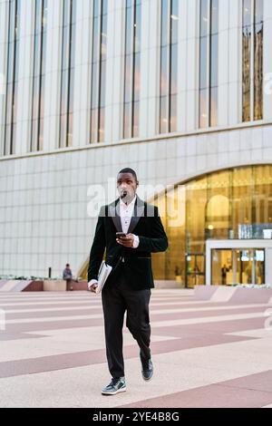 black businessman leaving office walking with suit and laptop in hand Stock Photo