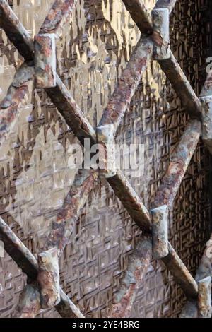 Close-Up of Rusty Metal Fence Against Textured Wall Stock Photo