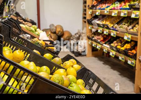 A fruit stand with a variety of fruits including lemons and oranges. The lemons are in a black basket and the oranges Stock Photo