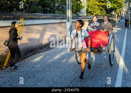 Young man pulling a rickshaw with passengers in kimonos in Kyoto on 27 September 2024 Stock Photo