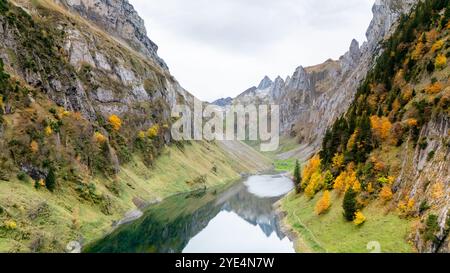 Nestled between towering mountains, the serene waters of Falensee reflect vibrant autumn colors, inviting tranquility and exploration in the breathtaking Swiss landscape. Stock Photo