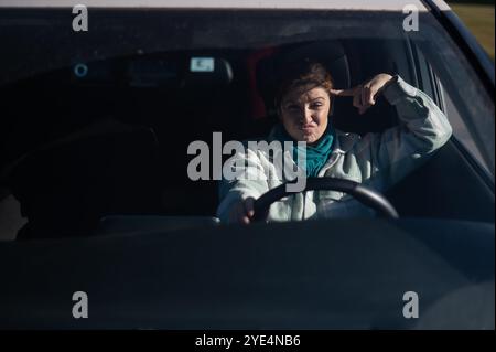 Caucasian woman twirls finger at temple while driving.  Stock Photo