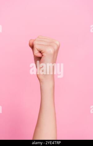 Cropped close up vertical portrait of lady raise hand fist empty space isolated on pink color background Stock Photo