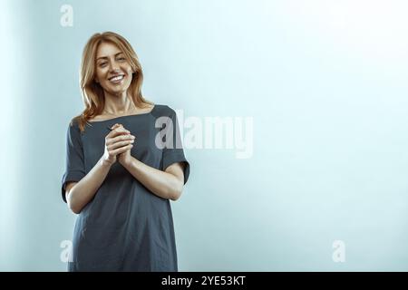 Cheerful teacher smiles confidently, holding a pen against a light blue background, radiating positivity and passion for education Stock Photo