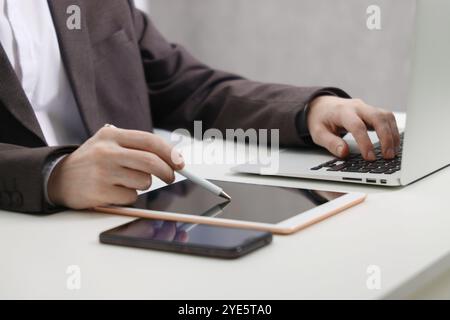 Businessman using different devices at white table indoors, closeup. Modern technology Stock Photo
