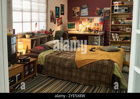 Comfortable study setup in cozy retro bedroom featuring a well-organized desk with various items and posters on wall, providing inspiration and functionality for studying environment Stock Photo