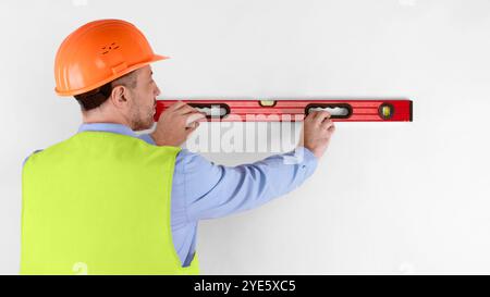 Housebuilder Using Building Level Standing Back To Camera, White Background Stock Photo