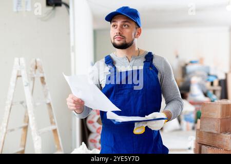 Foreman reading papers on indoor construction site Stock Photo