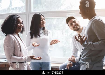 Cheerful multiracial colleagues having small talk in office Stock Photo