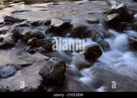 Environment. Fast-flowing crystal clear water flows by rocks in a large stream. Jamor River. Oeiras, Portugal. Photographic techniques, long exposure Stock Photo