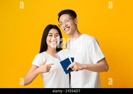 Happy young asian couple holding passports and tickets Stock Photo