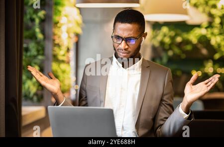 Surprised young afro manager looking at his computer Stock Photo
