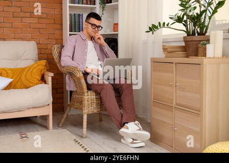Male author using laptop in armchair at home Stock Photo