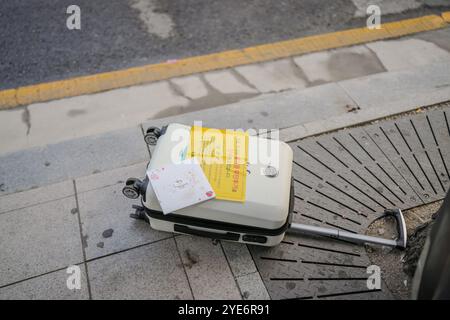 White suitcase with a yellow sign on it. The sign says "Please do not open." Stock Photo