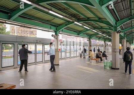 Group of people are standing in a train station. There are two men standing in front of a train Stock Photo