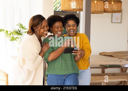 African american female friends laughing together at home, enjoying fun moment with tablet Stock Photo