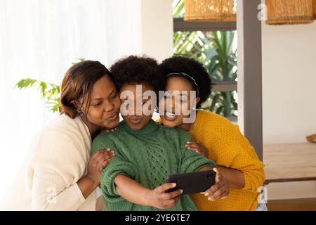 Taking selfie with smartphone, african american female friends at home with joyful expressions Stock Photo