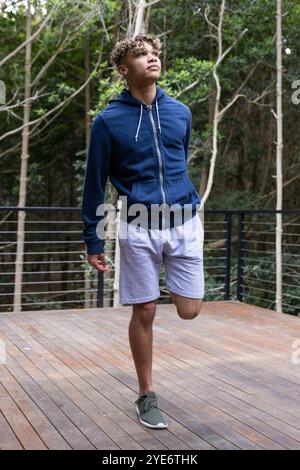 Young man in blue hoodie enjoying nature on wooden deck in forest Stock Photo