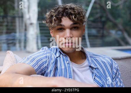 Relaxing outdoors, young man in striped shirt enjoying peaceful afternoon, at home Stock Photo