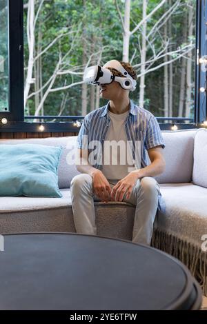 Christmas time, Relaxing at home, man using VR headset on cozy sofa by window Stock Photo