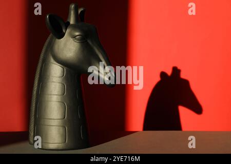 Decorative figure of giraffe on black table against red background with shadow Stock Photo