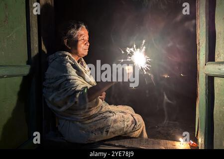 FENI, BANGLADESH - OCTOBER 17: A Hindu old woman playing with light during the 'Deep Utsav or Light festival' before the Diwali festival in Feni, Bang Stock Photo