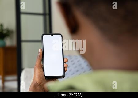 African American man holding smartphone with blank screen at home, copy space Stock Photo