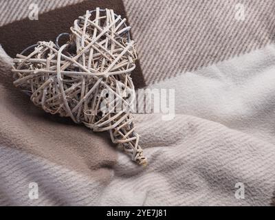 Woven wooden heart shape on a wool plaid with space for text Stock Photo