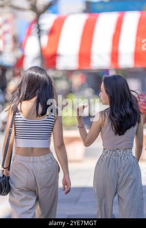 Two Taiwanese women in their 30s wearing casual outfits walk along Dihua Street in Taipei City, Taiwan, in September. Stock Photo
