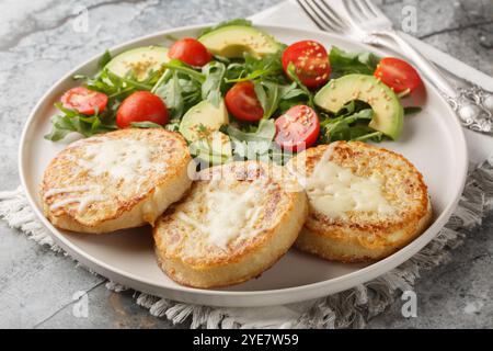 Fried crumpets in beaten egg with fresh vegetable salad for breakfast close-up in plate on table. Horizontal Stock Photo