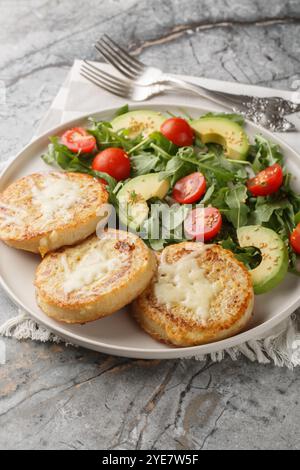 Eggy cheese crumpets with vegetables salad closeup on the plate on the table. Vertical Stock Photo