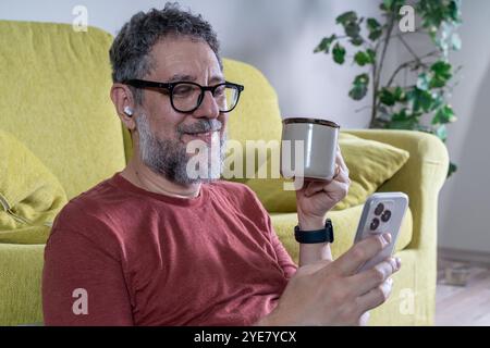 Contemporary mature man managing digital devices at home office. Natural lifestyle portrait of middle aged professional working remotely with modern t Stock Photo