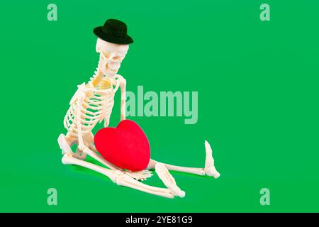 Skeleton figure with a heart, set against a vibrant green background, ideal for Valentine's Day themed content. Stock Photo