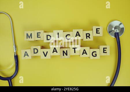 Medicare Advantage with wooden blocks alphabet letters and stethoscope on yellow background Stock Photo