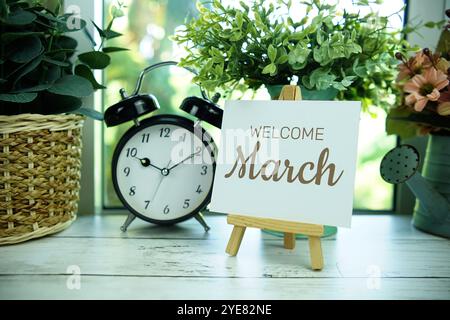 Welcome March text on paper card with easel and alarm clock in the window background Stock Photo