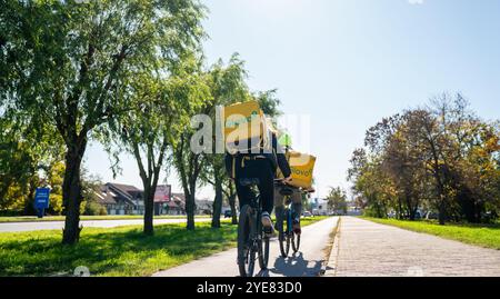 Rear view of Glovo food delivery cyclists on the street in Serbia: Novi Sad, Serbia - 10.18.2024 Stock Photo