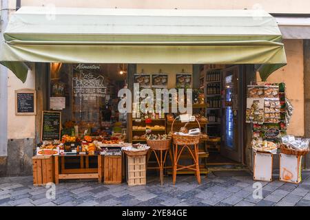 A grocery store selling local products, with fresh fruit, dried mushrooms, liqueurs and other typical foods displayed on the sidewalk, Aosta, Italy Stock Photo