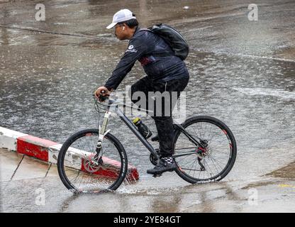 SAMUT PRAKAN, THAILAND, OCT 03 2024, A man rides a bicycle in the rain Stock Photo