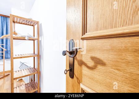 Open doors to laundry room in house. Opened wooden door with metal doorknob to closet Stock Photo