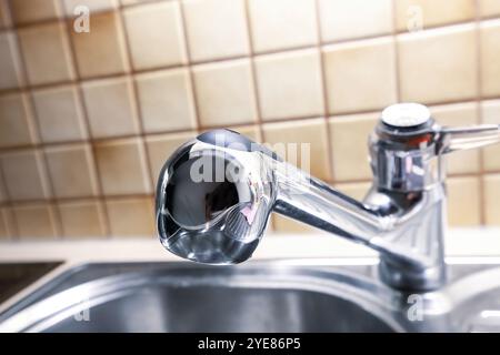 Metal faucet and sink on domestic kitchen closeup. Chrome water tap in home close up. Stainless steel handle tap in bathroom, selective focus Stock Photo
