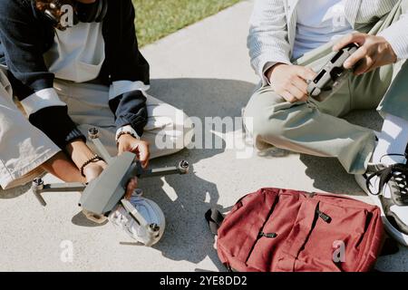 High angle shot of unrecognizable boys hands holding black drone and its remote controller while they spending spare time in park Stock Photo