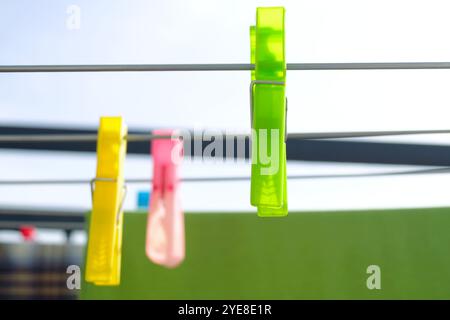 Drying clothes in the wind and sun: multi-colored plastic clothespins hanging on different metal rods of an outdoor drying rack, close-up Stock Photo