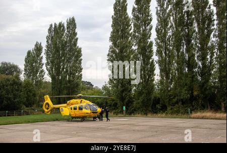 The bright yellow East Anglian Air Ambulance having responded to an emergency in Framlingham rural Suffolk waits with crew in a car park Stock Photo