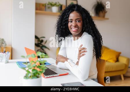 Young black woman smile at camera working with laptop at home Stock Photo