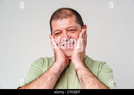 Happy middle-aged man showing joy while touching his face against a neutral background Stock Photo