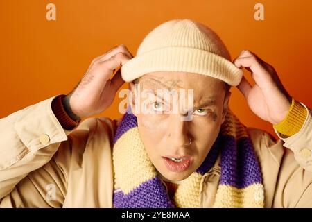 A young man with striking tattoos shows a surprised expression while adjusting his hat. Stock Photo