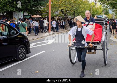 Young Japanese man pulling a rikshaw with passenger on board through the streets of Arashiyama, japan on 28 September 2024 Stock Photo