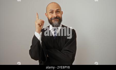 Handsome hispanic man making a bright idea gesture, isolated against a white wall background, with a bald head and beard, wearing a dark suit in a por Stock Photo