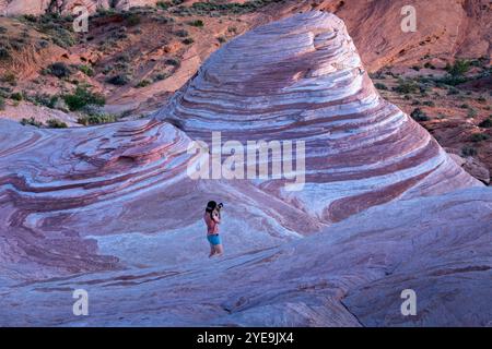 A young woman photographs the famous Fire Wave rock formation, Valley of Fire State Park, Nevada, United States of America, North America Stock Photo